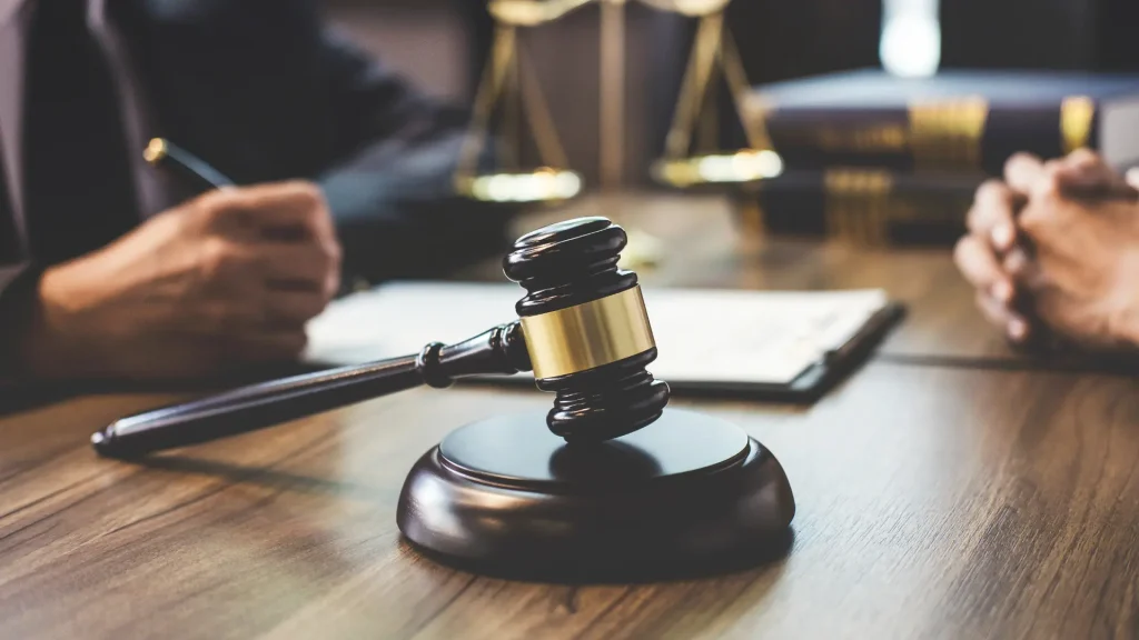 Close-up of a gavel on a wooden desk with legal scales in the background