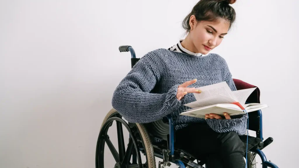 Young woman in a wheelchair reading a notebook