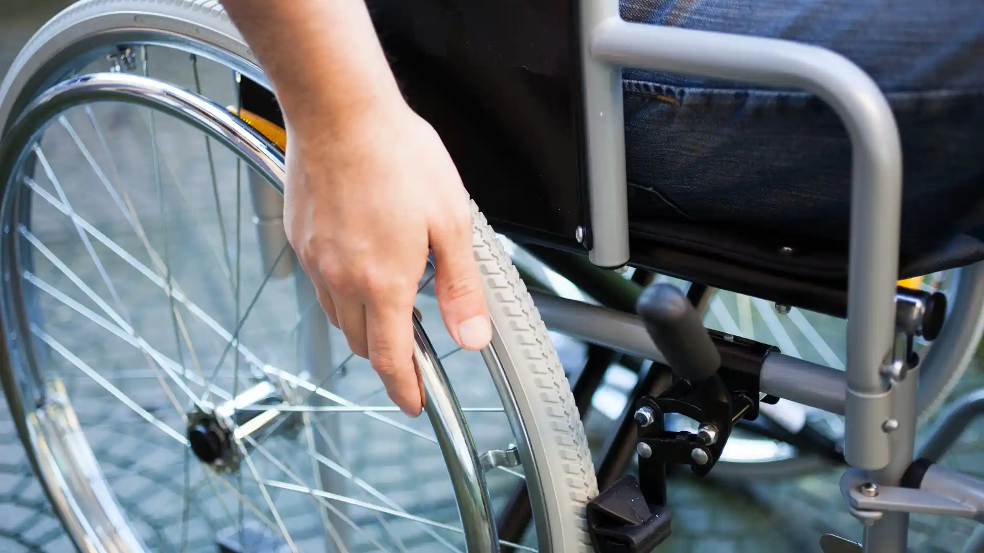 Hand gripping the tire of a wheelchair.