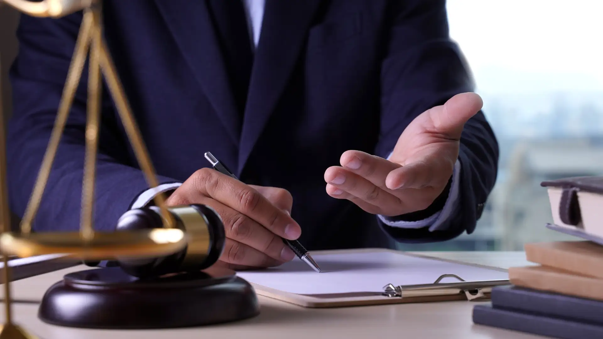 Lawyer writing on legal documents with a gavel on the desk.