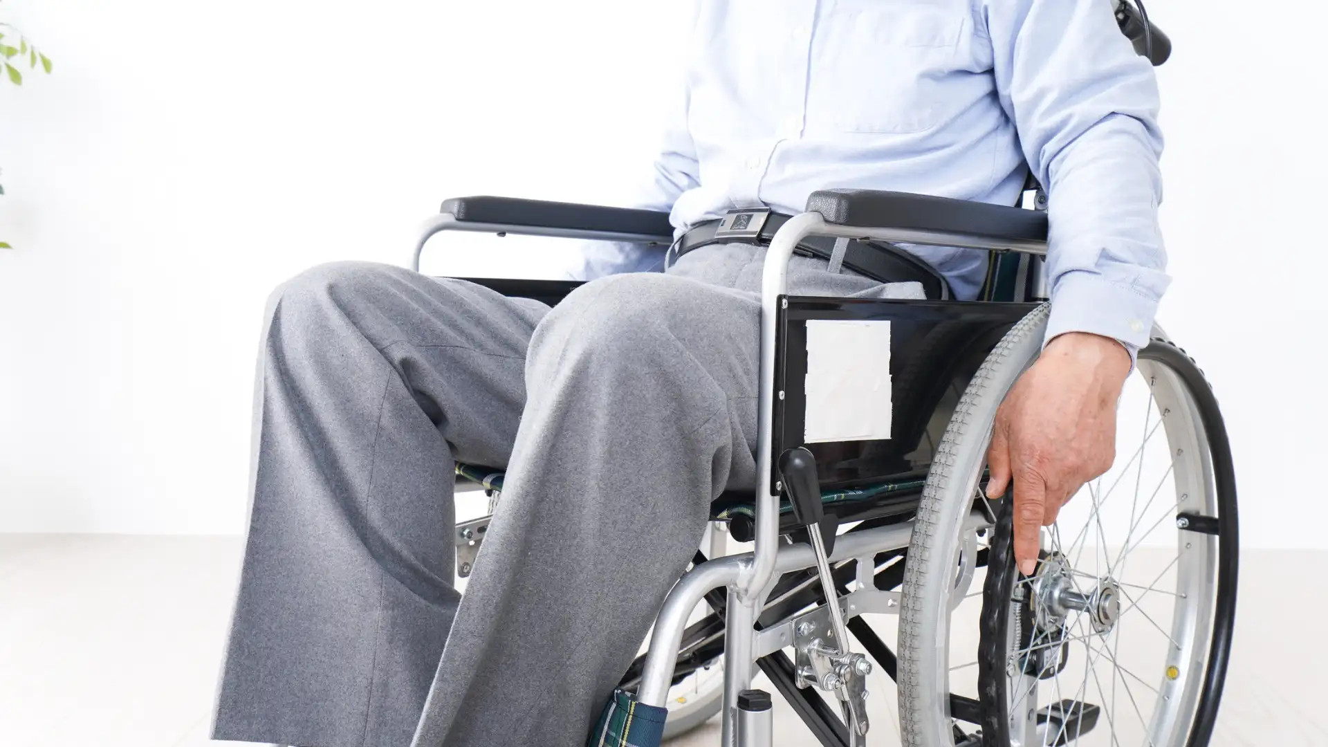 Man in a wheelchair wearing gray pants and a blue shirt.
